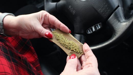 A woman wrapping weed to smoke and get high in a car